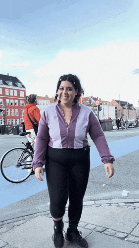 a woman in a purple jacket and black pants is walking down a sidewalk