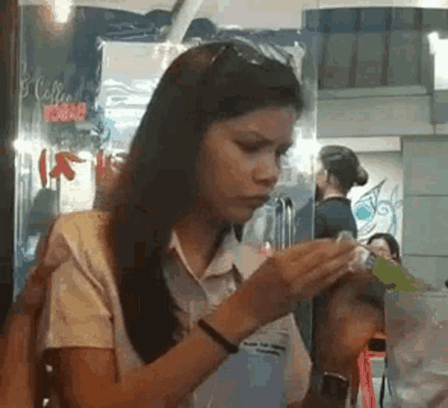 a woman is sitting at a table in a restaurant holding a bottle of water .