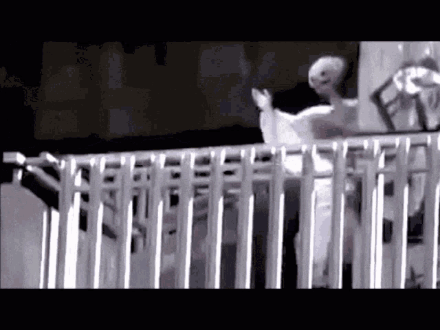 a man is standing on a balcony holding a white umbrella .