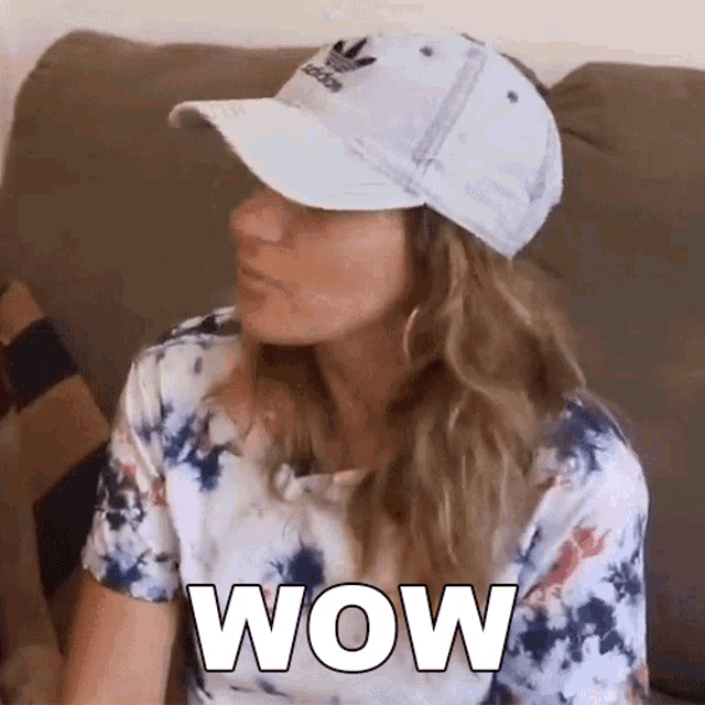 a woman wearing a hat is sitting on a couch and says wow .