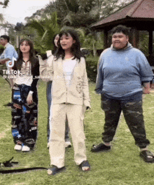 a group of people standing next to each other in a grassy area .