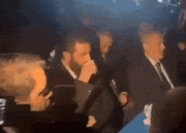 a group of men are sitting in a dark room .
