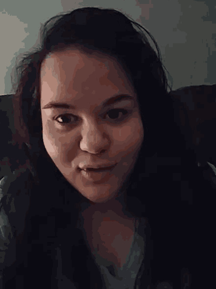a woman in a blue shirt is making a funny face with her eyes closed