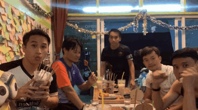 a group of men are sitting at a table with a sign that says open on it
