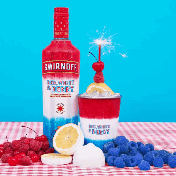 a bottle of smirnoff red white and berry next to a cup