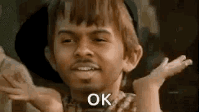 a man with a beard and a hat is making a funny face and saying `` ok '' .