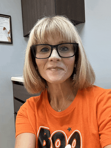 a woman wearing an orange shirt that says boo on it
