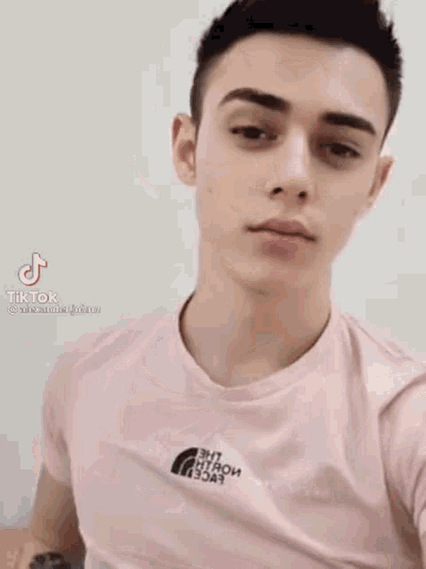 a young man is taking a selfie in a pink shirt .