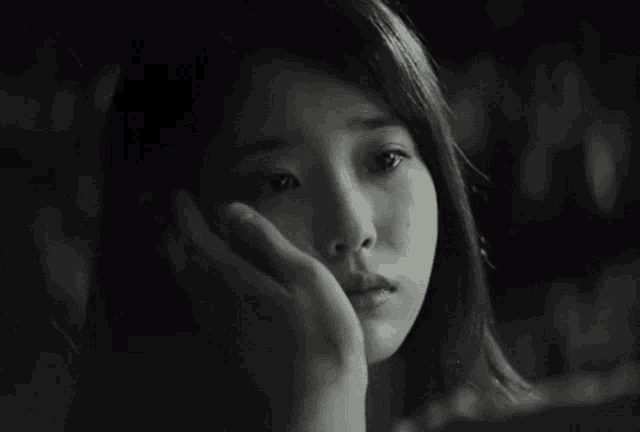 a black and white photo of a woman 's face with a hand on her face .
