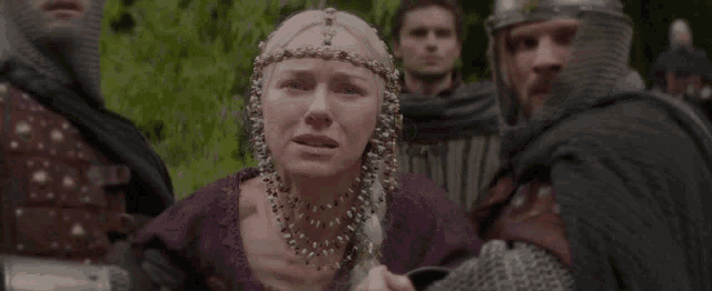 a woman in a purple dress is crying while wearing a headpiece