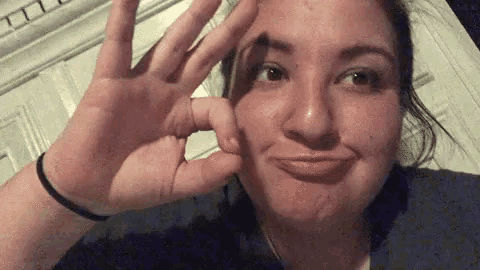 a woman is making a funny face while holding her hand up to her face .