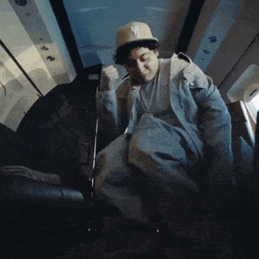 a man wearing a hat that says ny on it is sitting on a plane