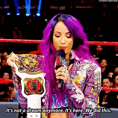 a woman with purple hair is holding a wrestling championship belt in a ring .