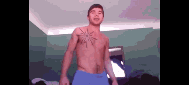 a shirtless man has a tattoo on his chest