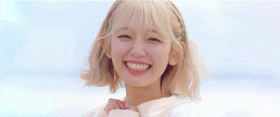 a young girl with pigtails is smiling and making a peace sign .