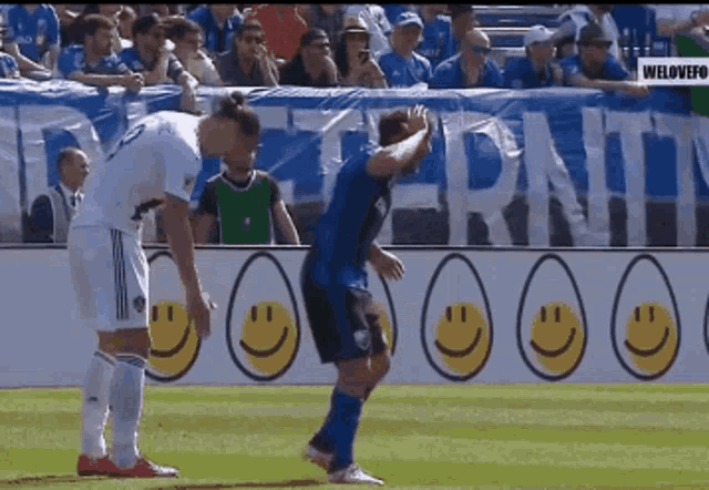 two soccer players on a field with smiley faces in front of them