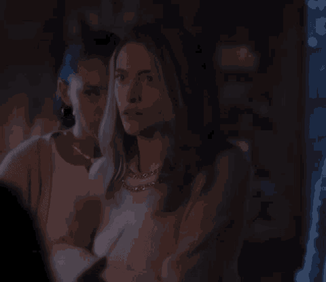 a woman in a white sweater is standing in a dark room .