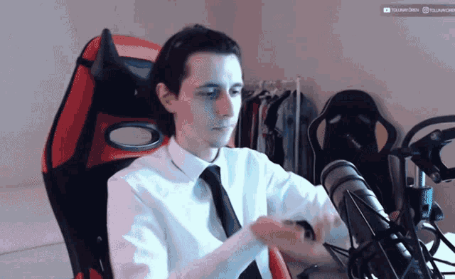 a man in a white shirt and tie sits in a red chair