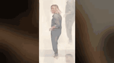 a woman is standing in a room with a blurred image of a man behind her .