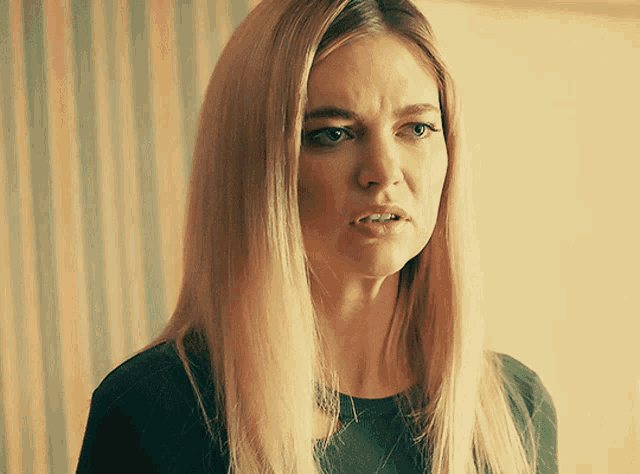 a woman with long blonde hair is making a face