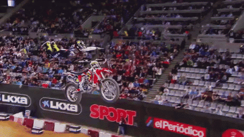 a man on a dirt bike is doing a trick in front of a sign that says sport