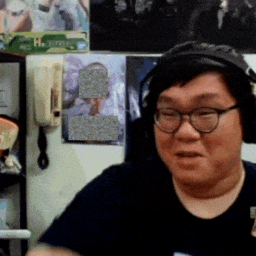 a man wearing glasses and headphones stands in front of a wall with a picture of a man on it