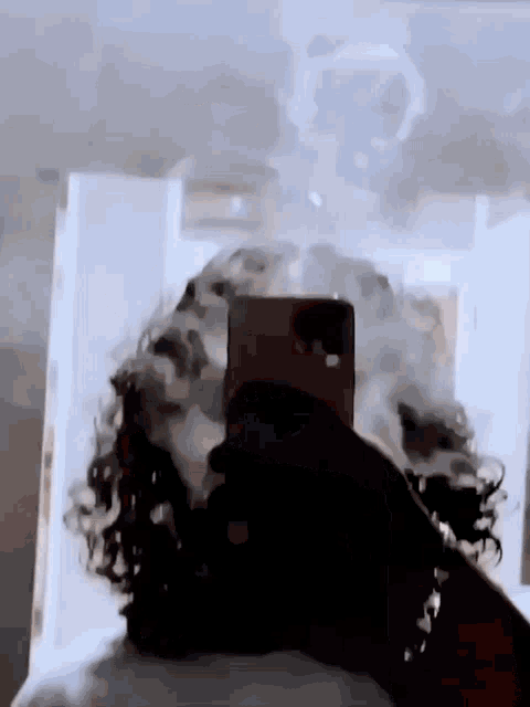 a person is taking a selfie with their cell phone while smoking a cigarette .
