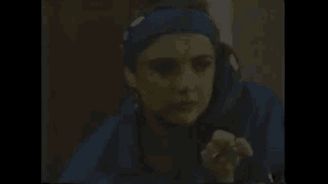 a woman wearing a blue headband is sitting in a dark room .