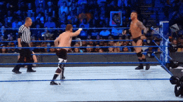 two men are wrestling in a ring with a referee watching .