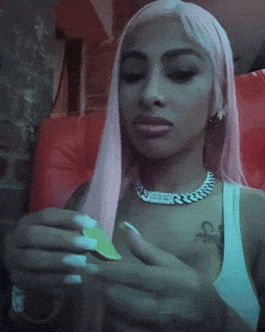 a woman with pink hair is wearing a necklace that says ' ice cube ' on it