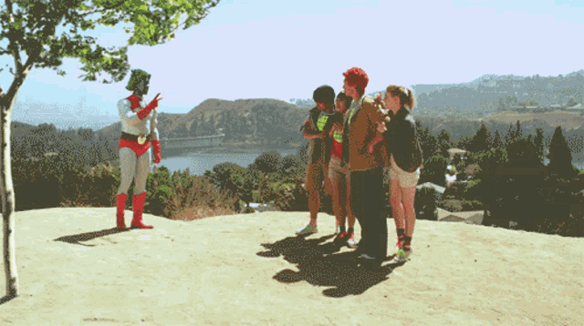 a group of people standing on top of a hill watching a superhero