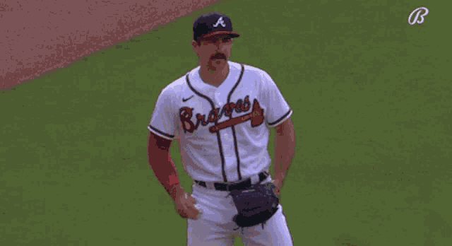 a man wearing a braves jersey stands on the field