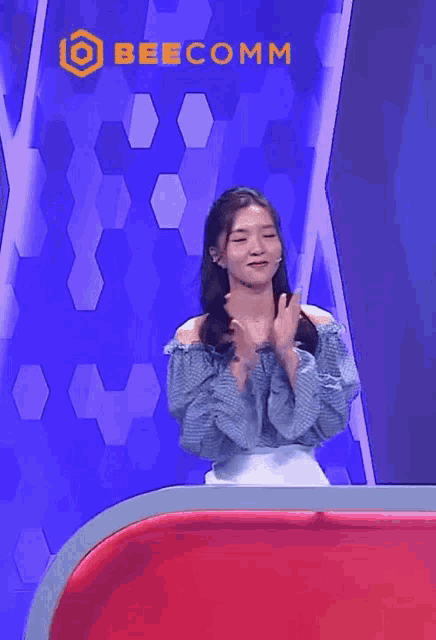 a woman applauds in front of a beecomm sign