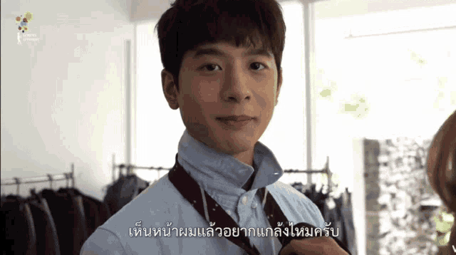 a man wearing a blue shirt and a red tie with a foreign language written below him