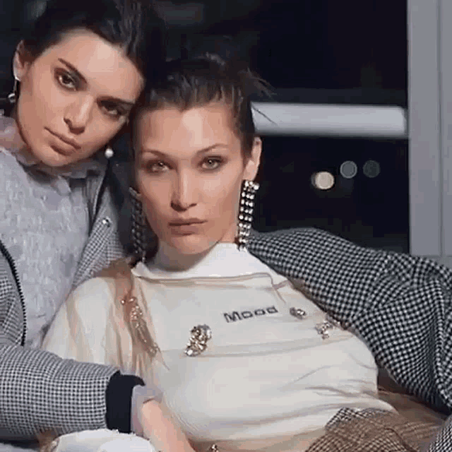 a couple of women sitting next to each other with one wearing a shirt that says mood