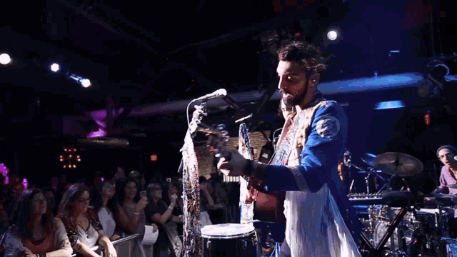 a man in a military uniform is playing a guitar in front of a crowd
