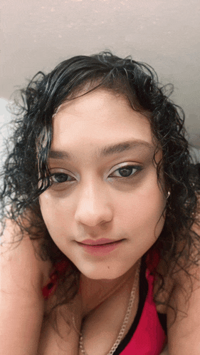 a woman with curly hair is wearing a red top