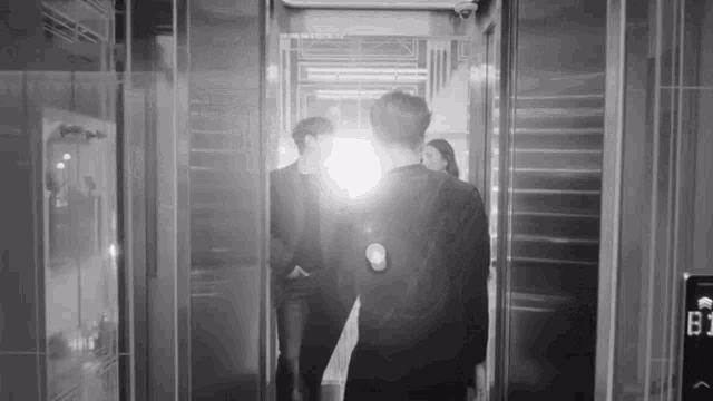 a group of people are walking out of an elevator with a light shining on them .
