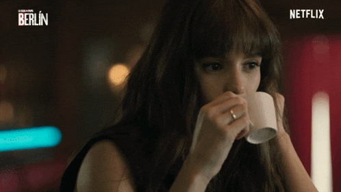 a woman drinking from a cup with a netflix logo in the corner