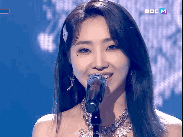 a woman singing into a microphone on a screen that says mbc m.