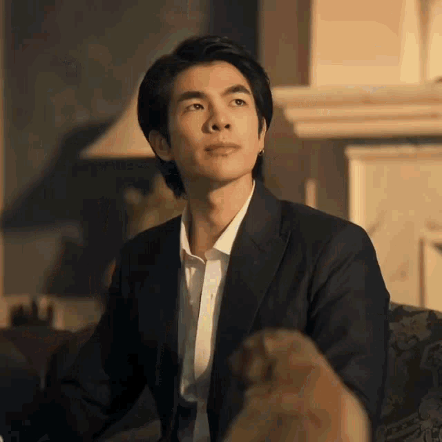 a man in a suit and white shirt is sitting on a couch with a dog .