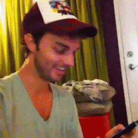 a man wearing a hat with the word ed hardy on it looks at his phone