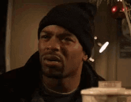 a man wearing a black beanie is looking at the camera .