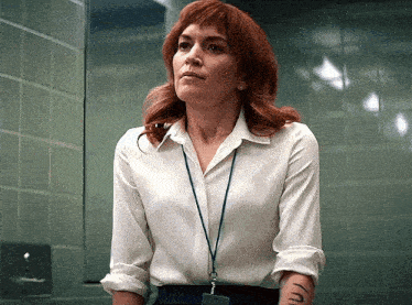 a woman with red hair is wearing a white shirt and a lanyard
