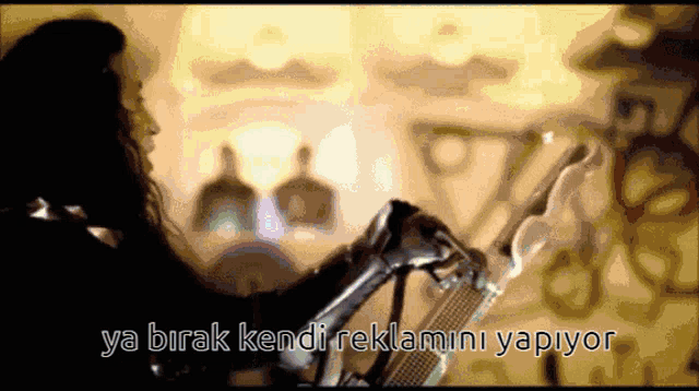 a woman playing a guitar with the words ya birak kendi reklamini yapiyor written below her