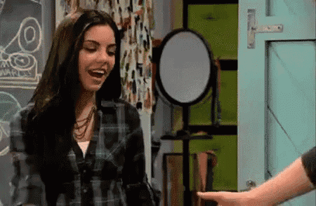 a woman in a plaid shirt is laughing and pointing at a man 's hand .