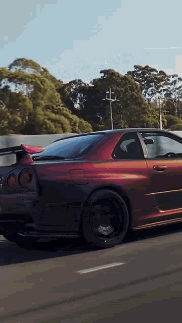 a purple and black sports car is driving down a road .