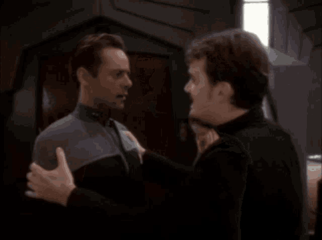 two men are hugging each other in a dark room .