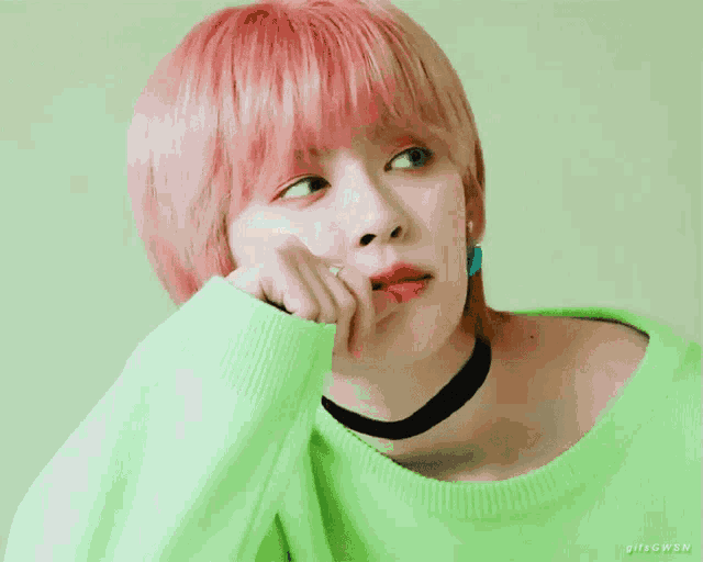 a woman with pink hair wearing a green sweater