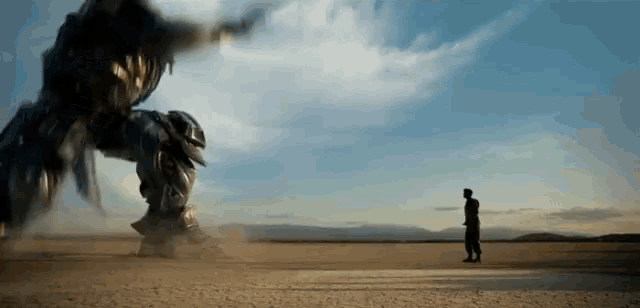 a man is standing in a desert looking at a robot